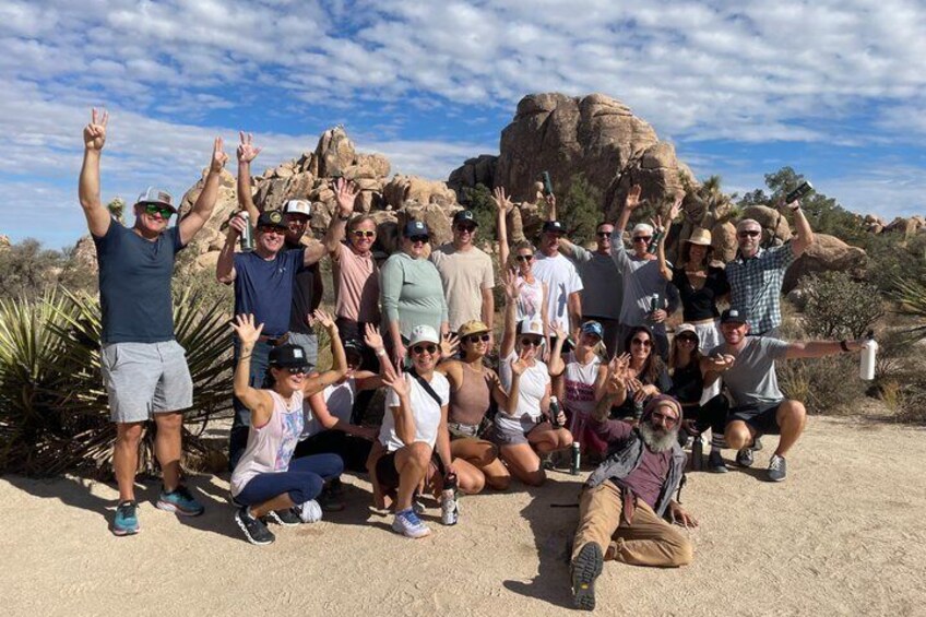 A group of people posing in a desert landscape with rocky formations in the background. 2