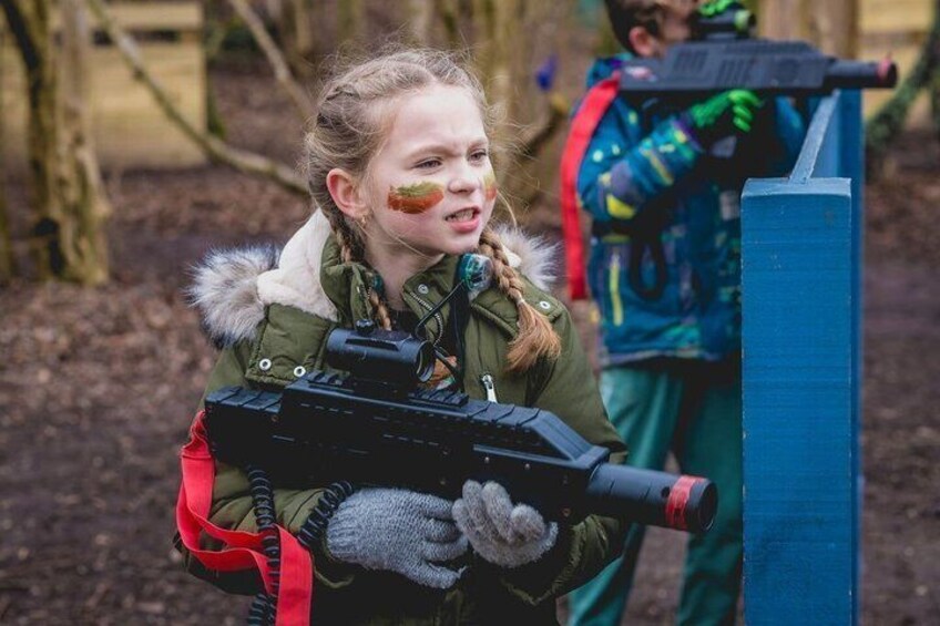 A person holding a toy gun, wearing a green jacket with a fur-lined hood, and gloves. 4