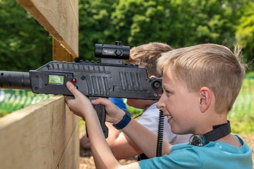 A person aiming a rifle with a scope at a wooden target. 2