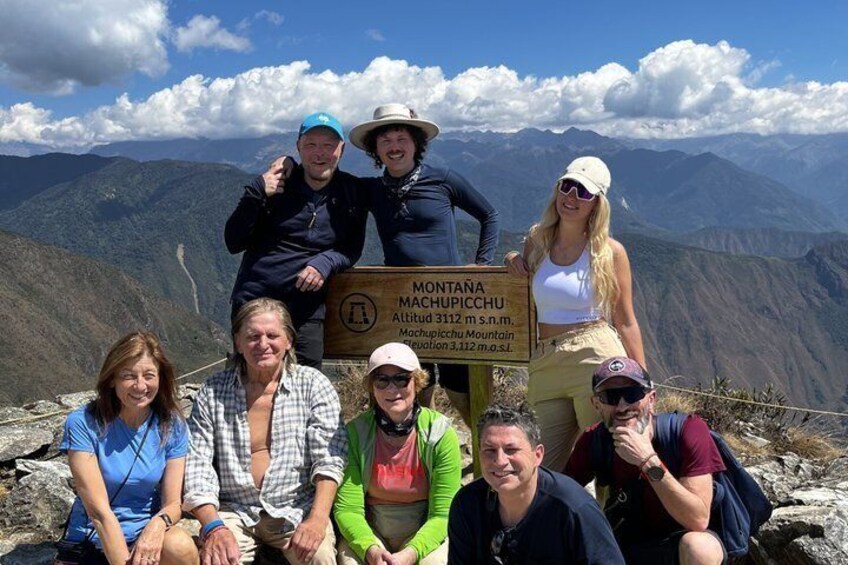 A group of people posing with a sign indicating the location of Montaña Machupicchu. 2