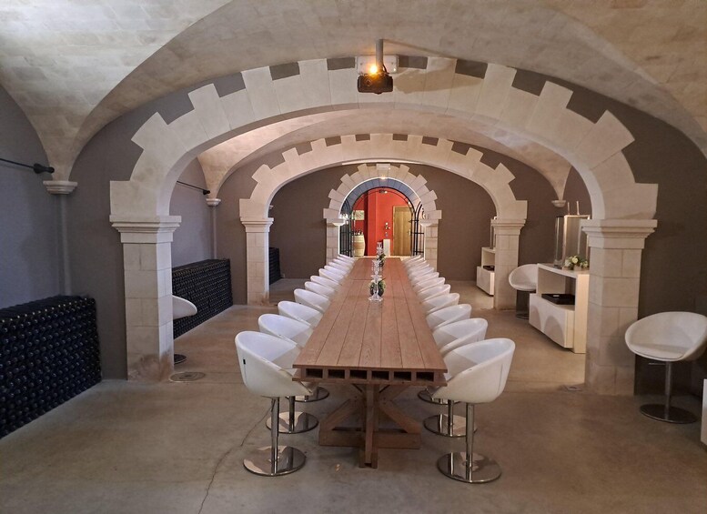 A long wooden table with white chairs in a room with arched ceilings and stone walls. 5