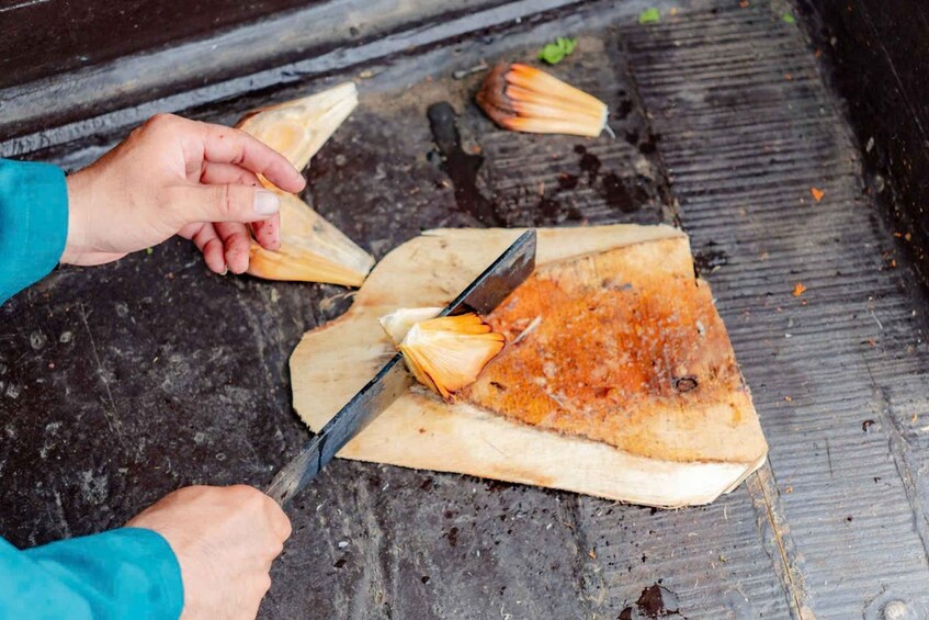 A person cutting a triangular food item on a wooden surface. 5