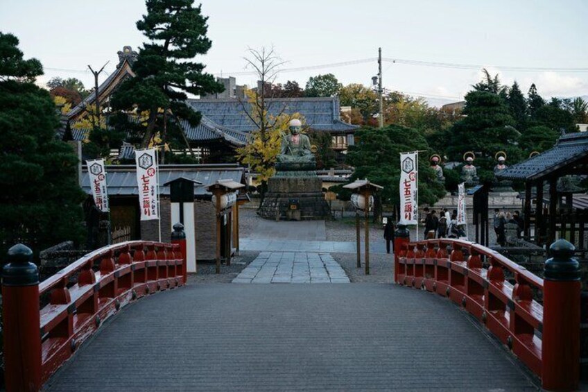 A traditional Japanese gate with red railings, a stone pathway, and a shrine in the background. 2