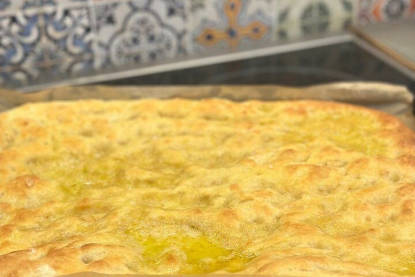 A large, round, baked dish with a golden-brown crust, possibly a savory pie or casserole, on a baking tray. 2