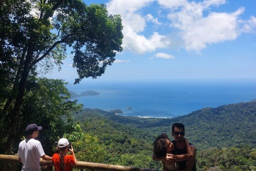 A group of people on a forested hill overlooking a coastal landscape with visible islands. 3
