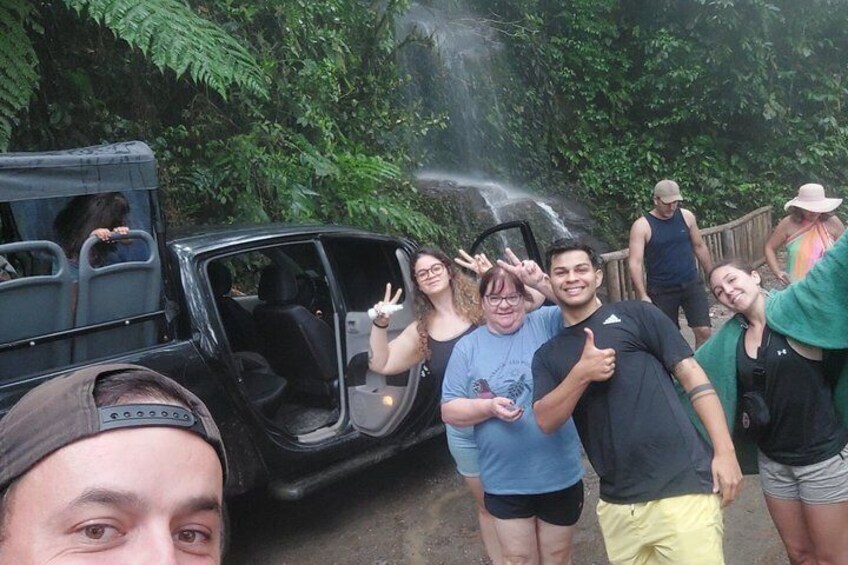 A group of people near a waterfall with a vehicle parked nearby. 2