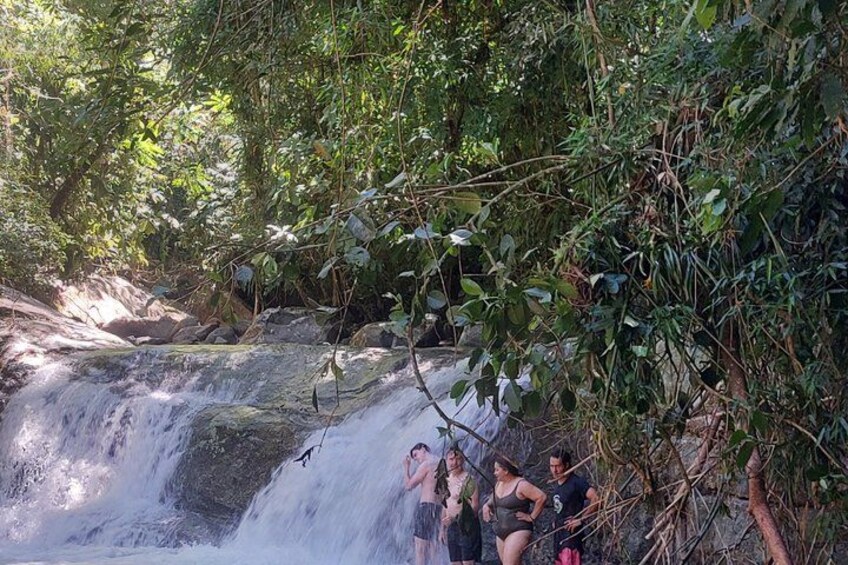 A waterfall with people standing on a rock ledge. 5