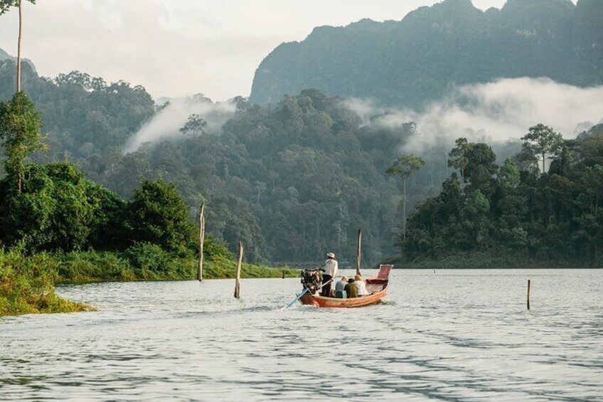 A boat on a calm river with dense forest and mist-covered mountains in the background. 1