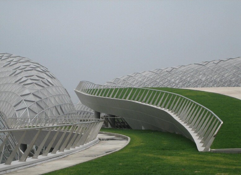 A modern architectural structure with a curved design and a green field in the foreground. 5