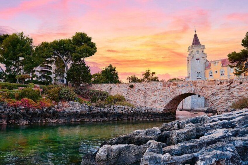 A stone bridge over water, a tower, and a sunset sky. 3