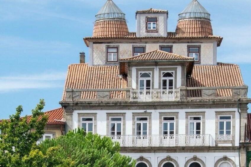 A historic building with a symmetrical facade, a central balcony, and two domed towers. 5