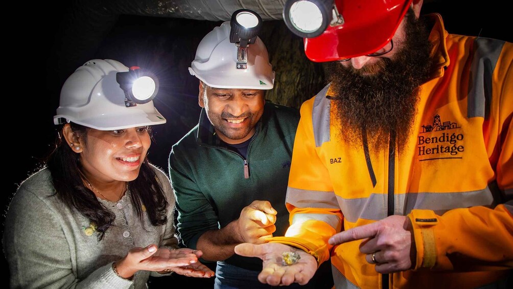 Three people wearing hard hats and safety vests, examining something in their hands. 1