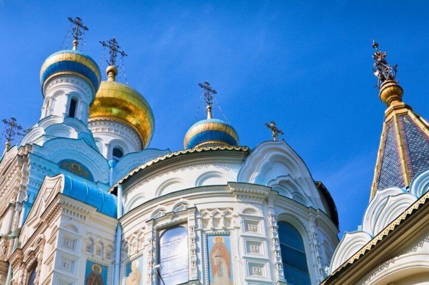 A church with multiple domes, one golden and others blue and white, under a clear blue sky. 4