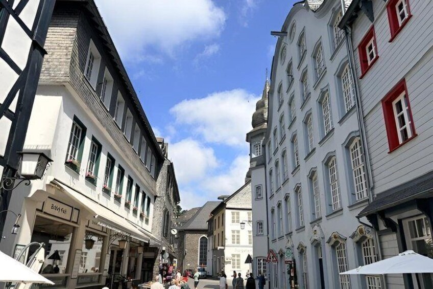 A narrow street with historic buildings, a clear sky, and a few pedestrians. 5