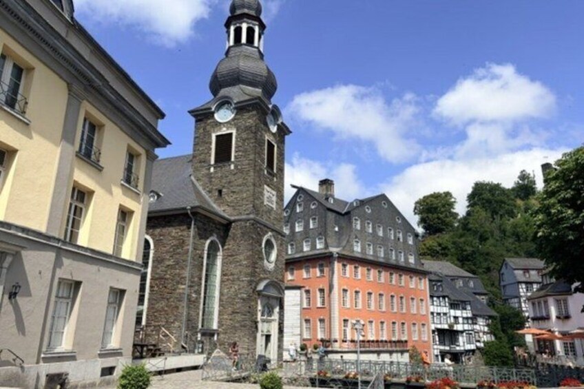 A historic church with a prominent tower, adjacent colorful buildings, and a clear blue sky. 3