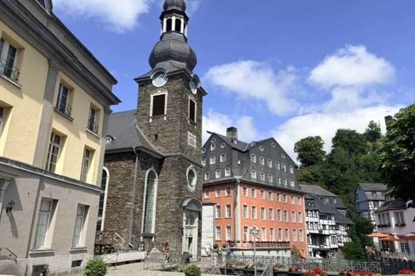A church with a tall steeple, a red building with white trim, and a yellow building with a balcony. 5