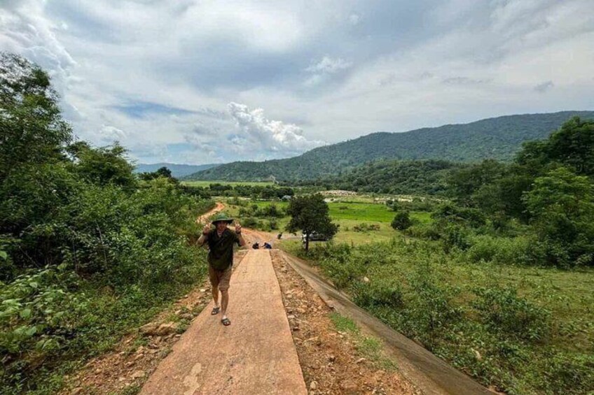 A person walking on a dirt path surrounded by greenery and hills. 5