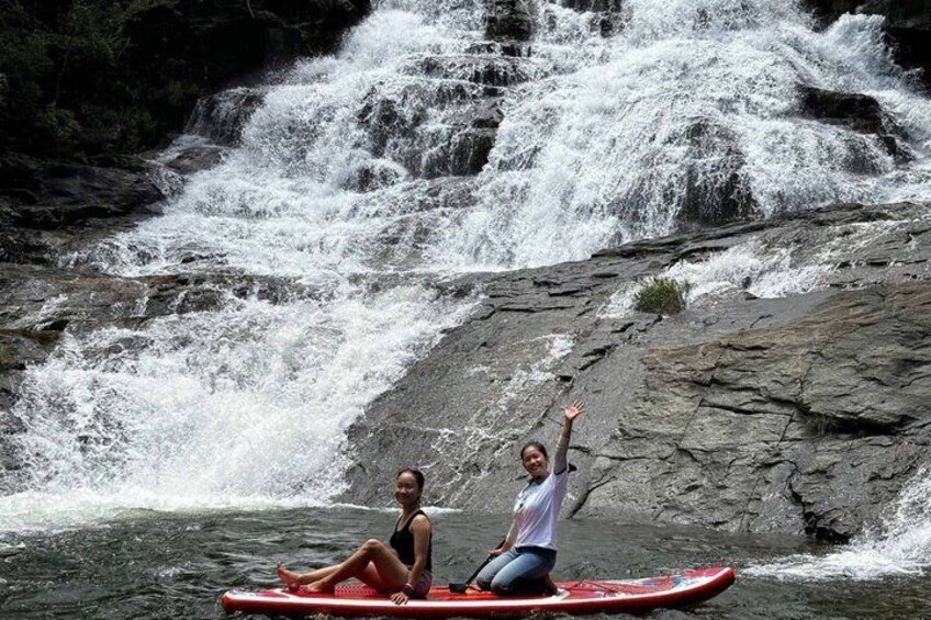 Two people on a red kayak in front of a waterfall. 1