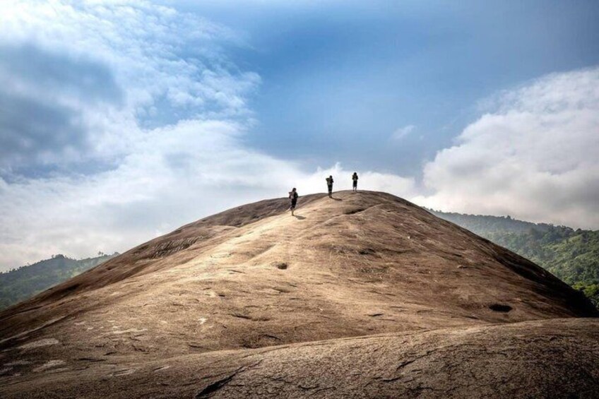 A large rock formation with two people standing on top. 1