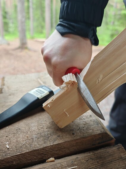 A person using a knife to cut a piece of wood. 3