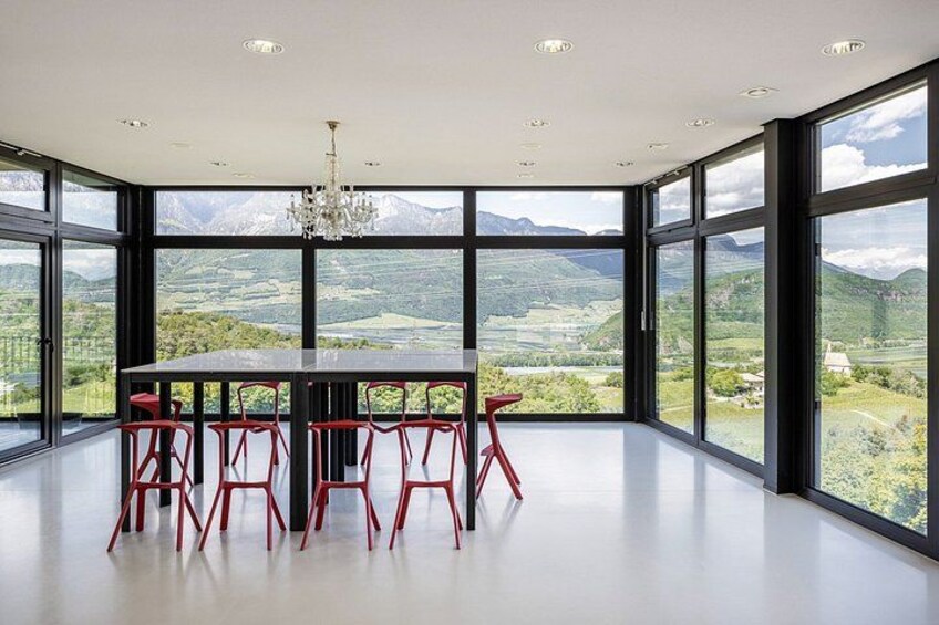 A dining area with a table and chairs, large windows, and a chandelier. 1