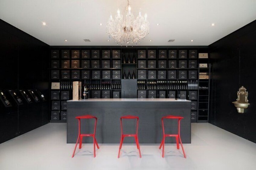 A bar with a black interior, red bar stools, and a chandelier. 3
