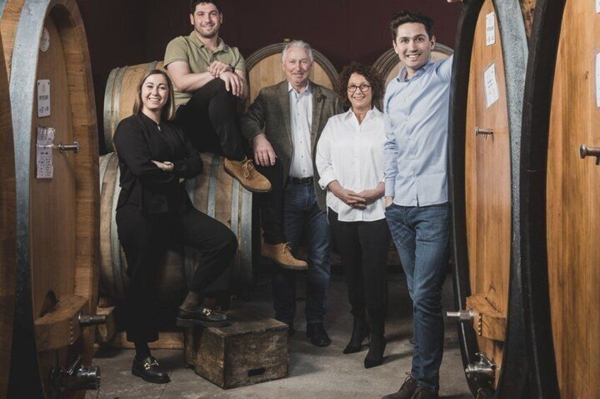 A group of people standing in a wine cellar with wooden barrels. 2