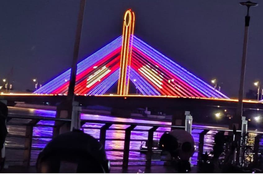 A brightly lit bridge with colorful lights at night. 2