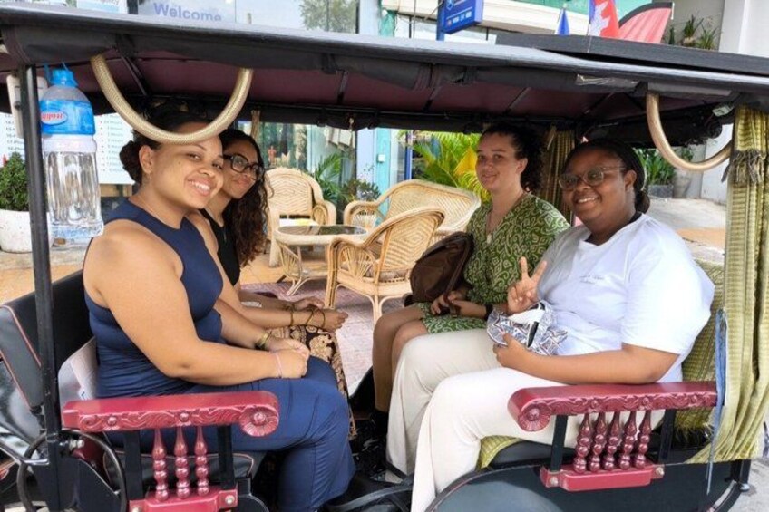 A group of people seated in a vehicle with wicker chairs and a red decorative element. 1
