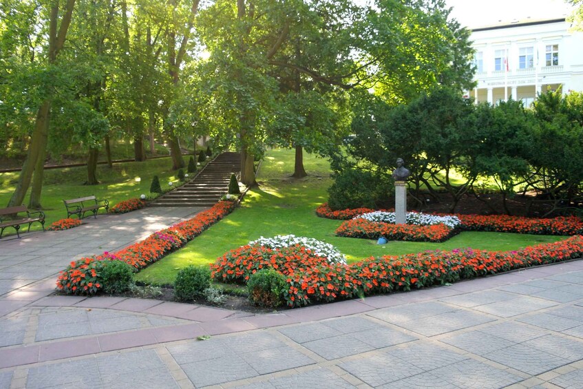 A park with a paved pathway, benches, and flower beds. 5