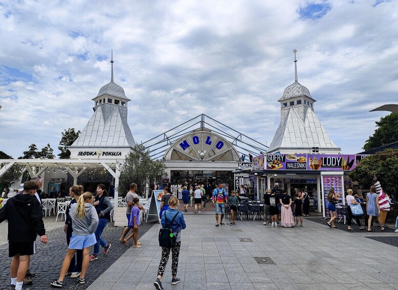 A busy outdoor market with food stalls and a prominent dome-shaped building labeled 'MODO'. 2
