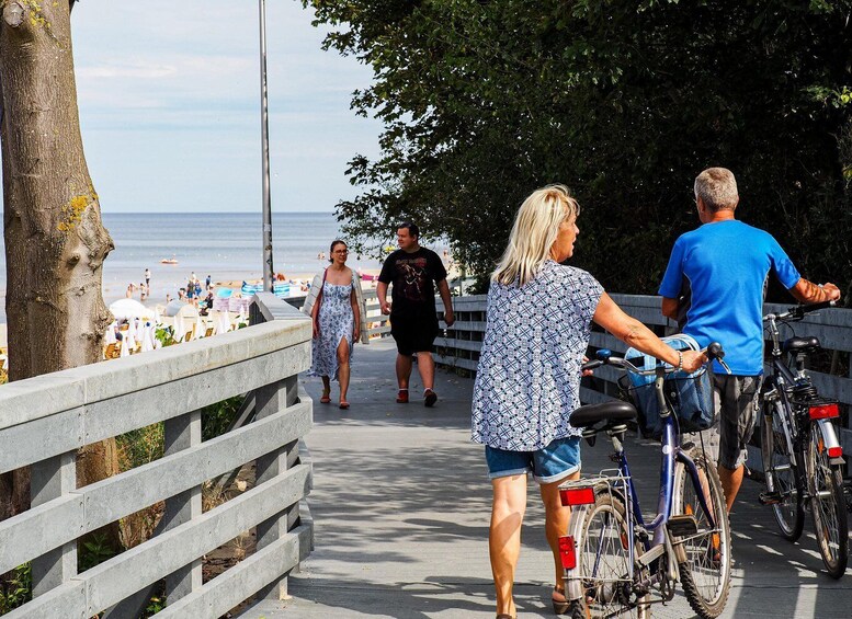 A coastal walkway with people walking, a bicycle, and a beach in the background. 4