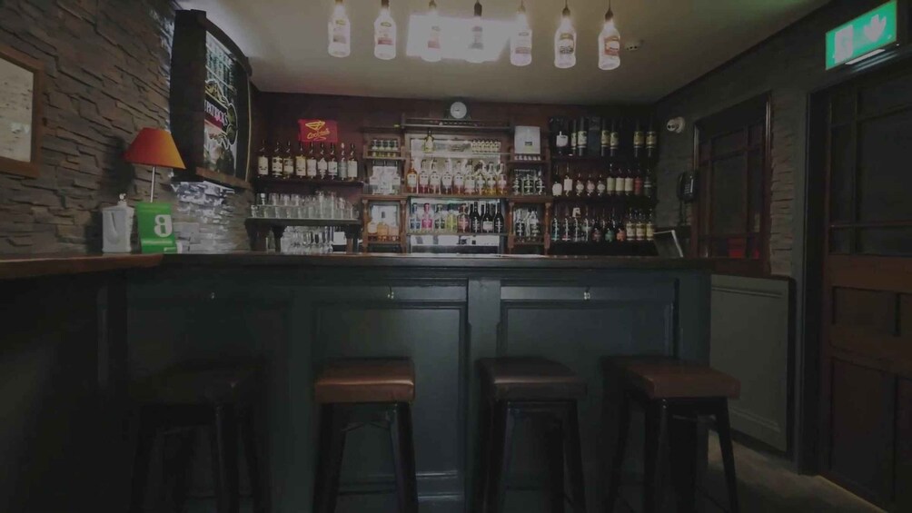 A bar with stools, bottles, and a sign. 2