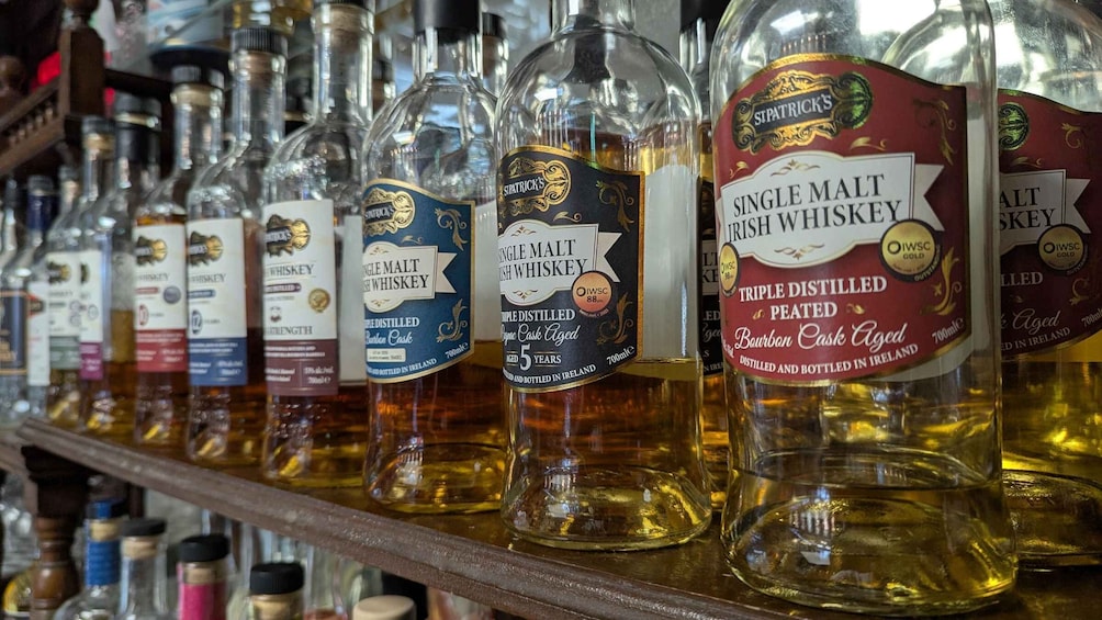 A variety of whiskey bottles on a shelf. 1