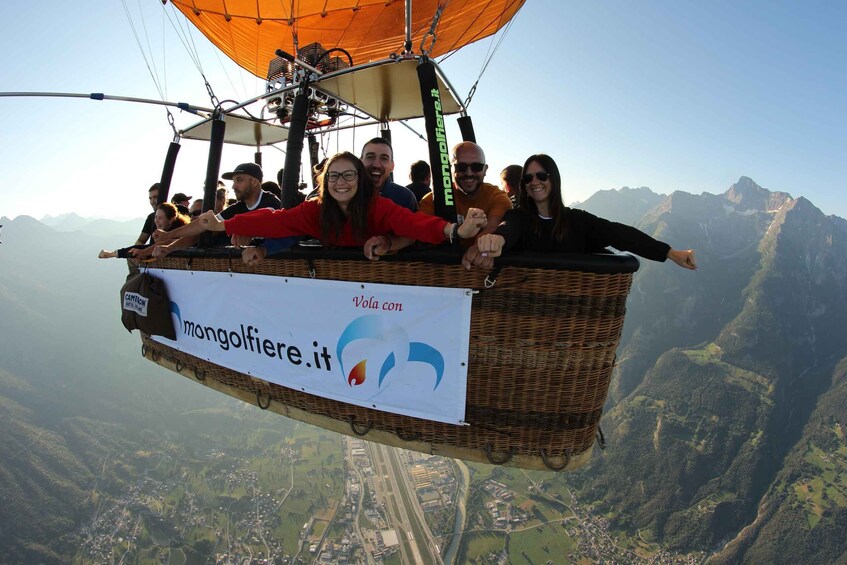 A wicker basket with people on a hot air balloon, flying over a mountainous landscape. 5