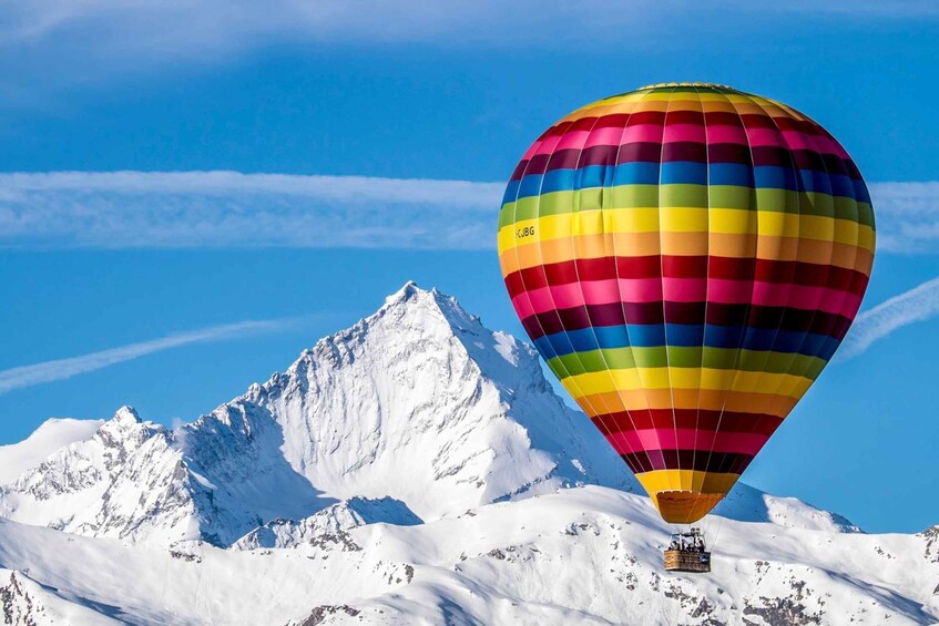 A colorful hot air balloon over a snow-covered mountain. 1