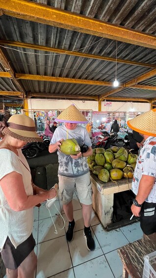 A market scene with people buying coconuts and a sign for a fashion store. 4