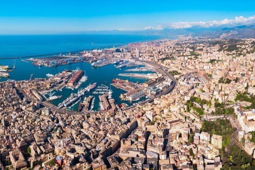 An aerial view of a coastal city with a dense urban area, a marina with boats, and a clear blue sky. 2