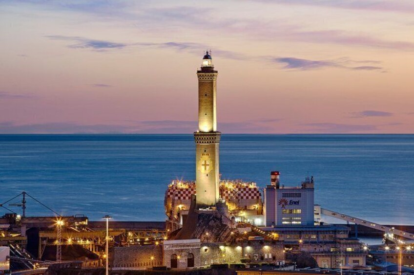 A lighthouse with a checkered pattern at its base, a building with the Enel logo, and a coastal cityscape at dusk. 5