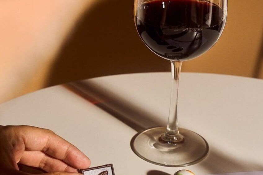 A wine glass on a table with a hand reaching for a menu. 2