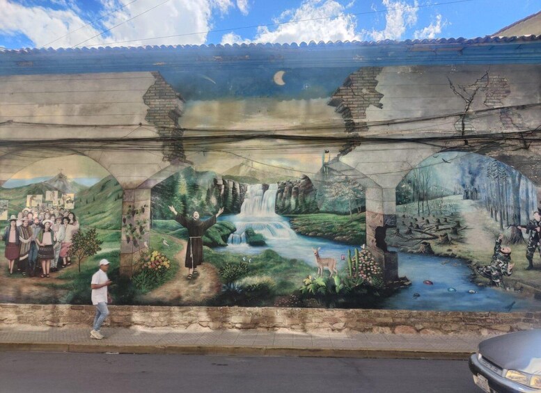 A mural with a waterfall, greenery, and a bridge. 5