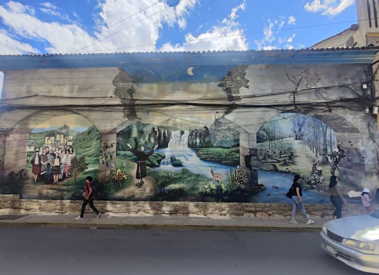 A mural with a waterfall, a bridge, and a group of people. 2