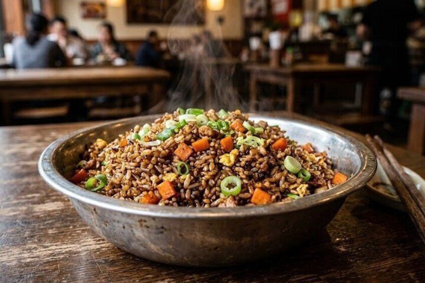 A bowl of fried rice with vegetables and green onions on a wooden table in a restaurant. 3