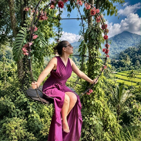 A person in a purple dress sitting on a swing surrounded by lush greenery and flowering plants. 5