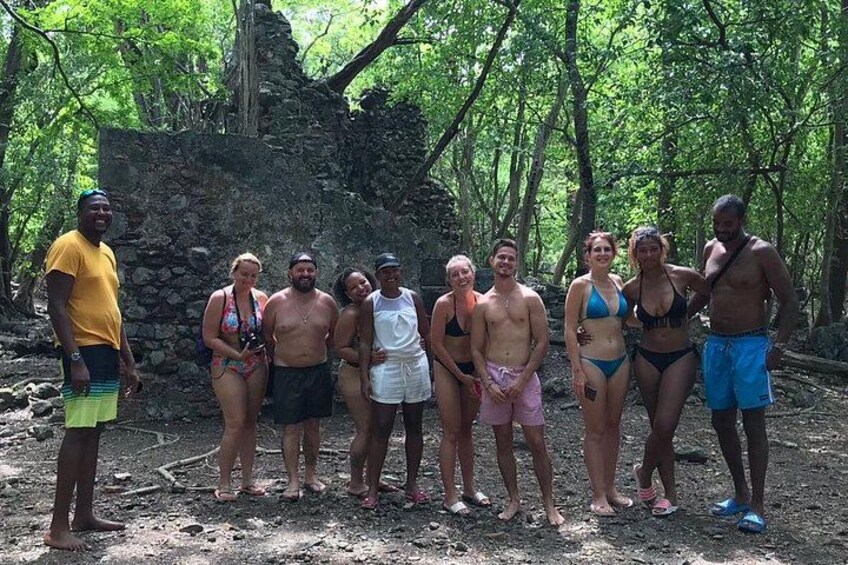 A group of people standing in a forested area with a stone structure in the background. 2