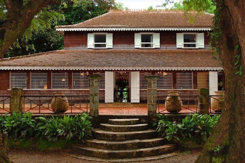 A traditional two-story house with a tiled roof, a front porch, and a stone staircase leading to the entrance. 2