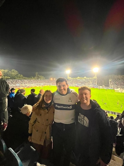 A stadium with a crowd of spectators, a football field, and floodlights. 1