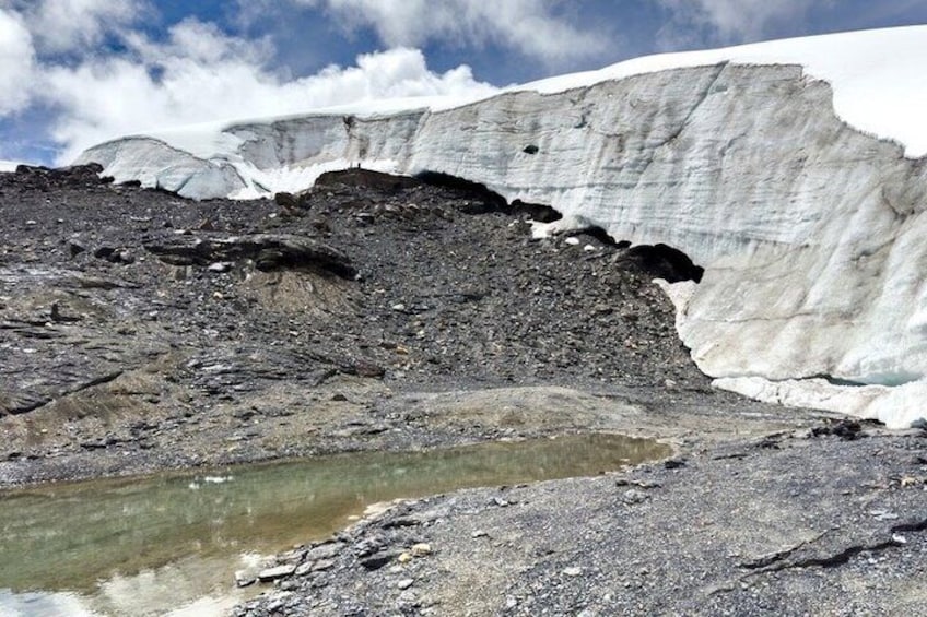 A glacier with a rocky foreground and a small body of water. 5