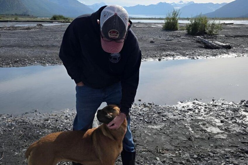 A person with a dog by a lake with mountains in the background. 2