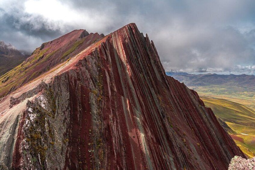 A rugged mountain peak with a steep, rocky surface and a dramatic sky. 5